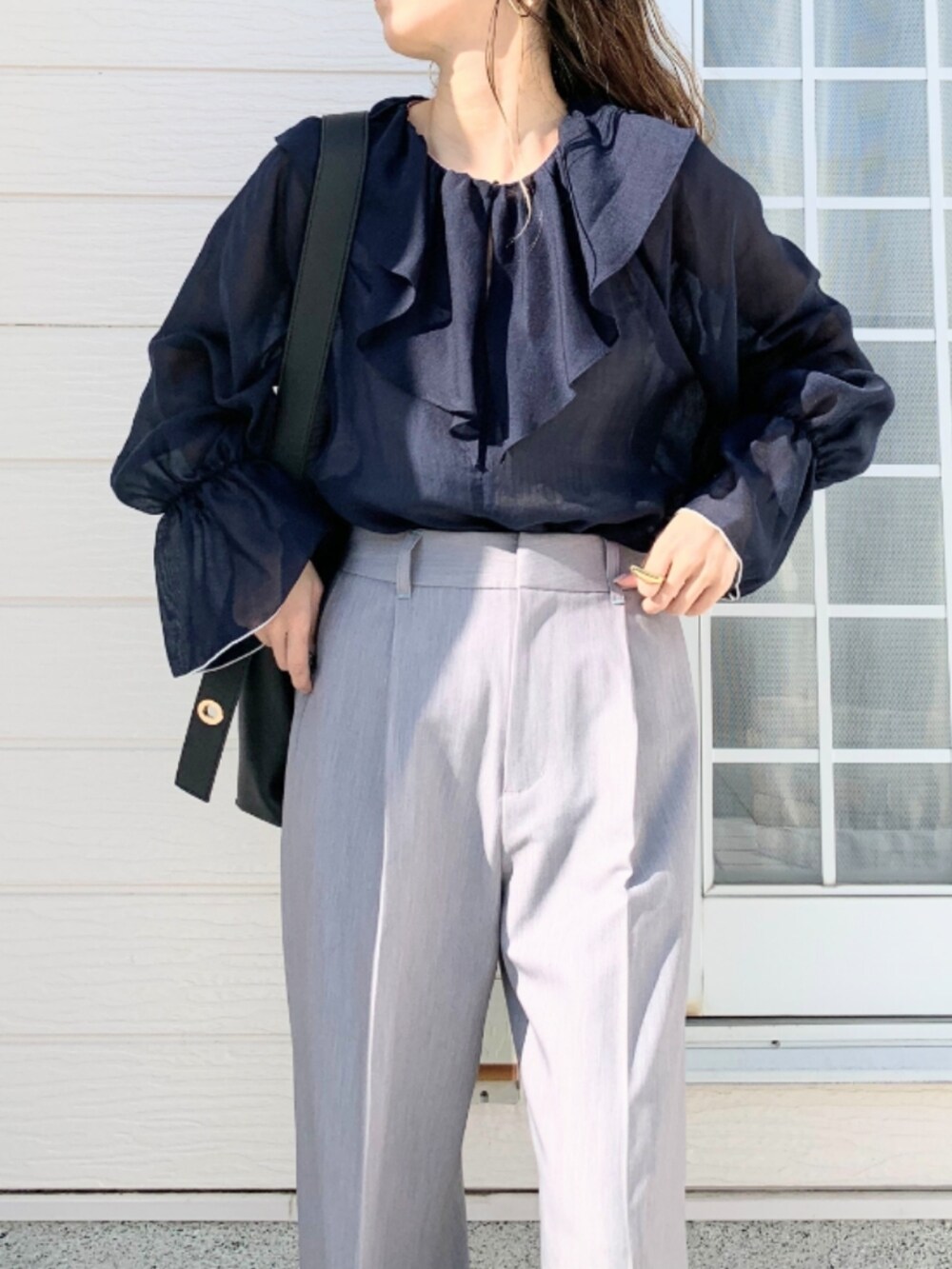 グレー系のスラックス、ブラック系のトートバッグ、ブルー系のシャツ/ブラウスを着用したレディースの春コーディネートの3枚目の写真