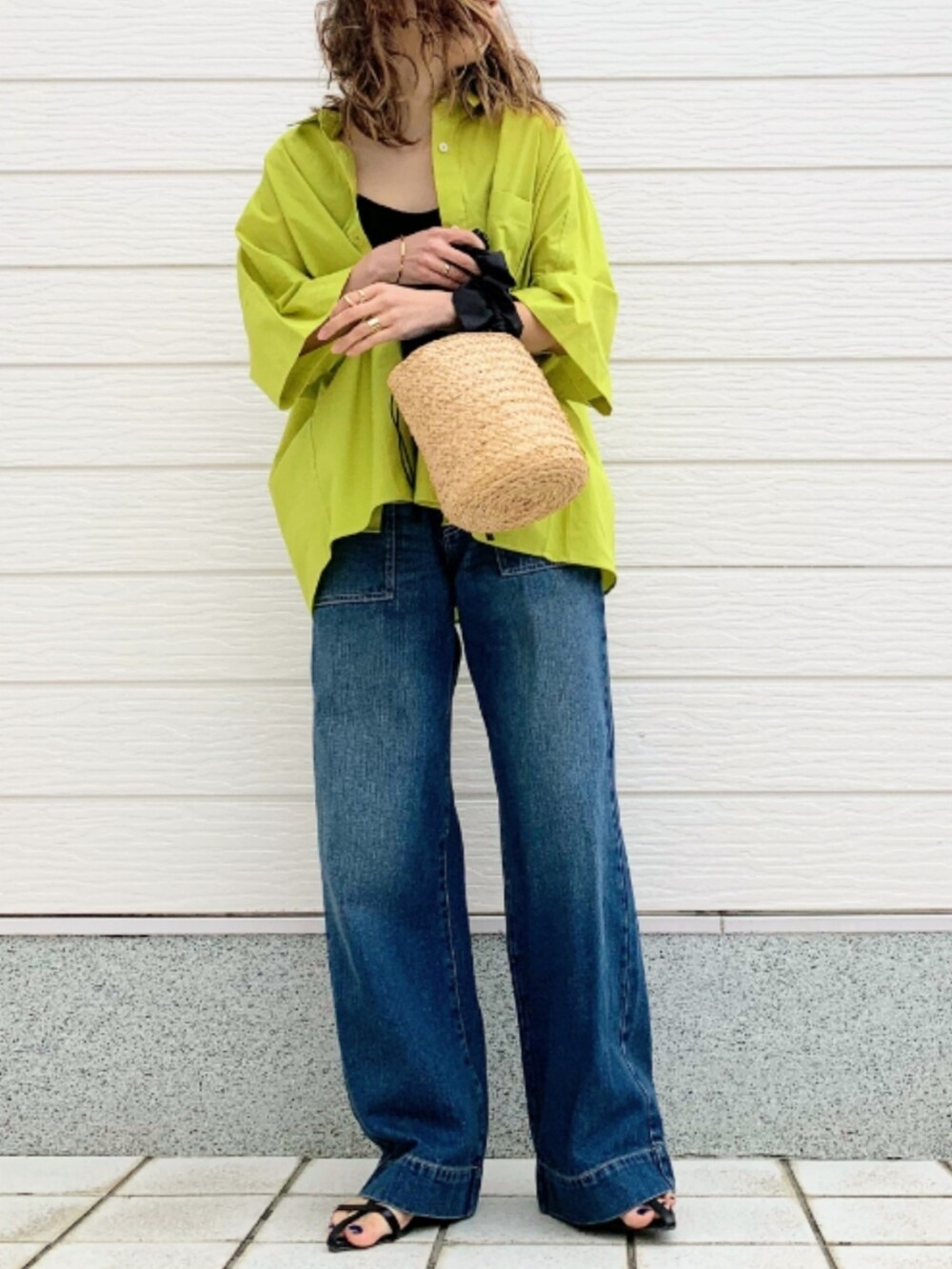 ブルー系のデニムパンツ、ブラック系のかごバッグ、グリーン系のシャツ/ブラウスを着用したレディースの春コーディネートの2枚目の写真