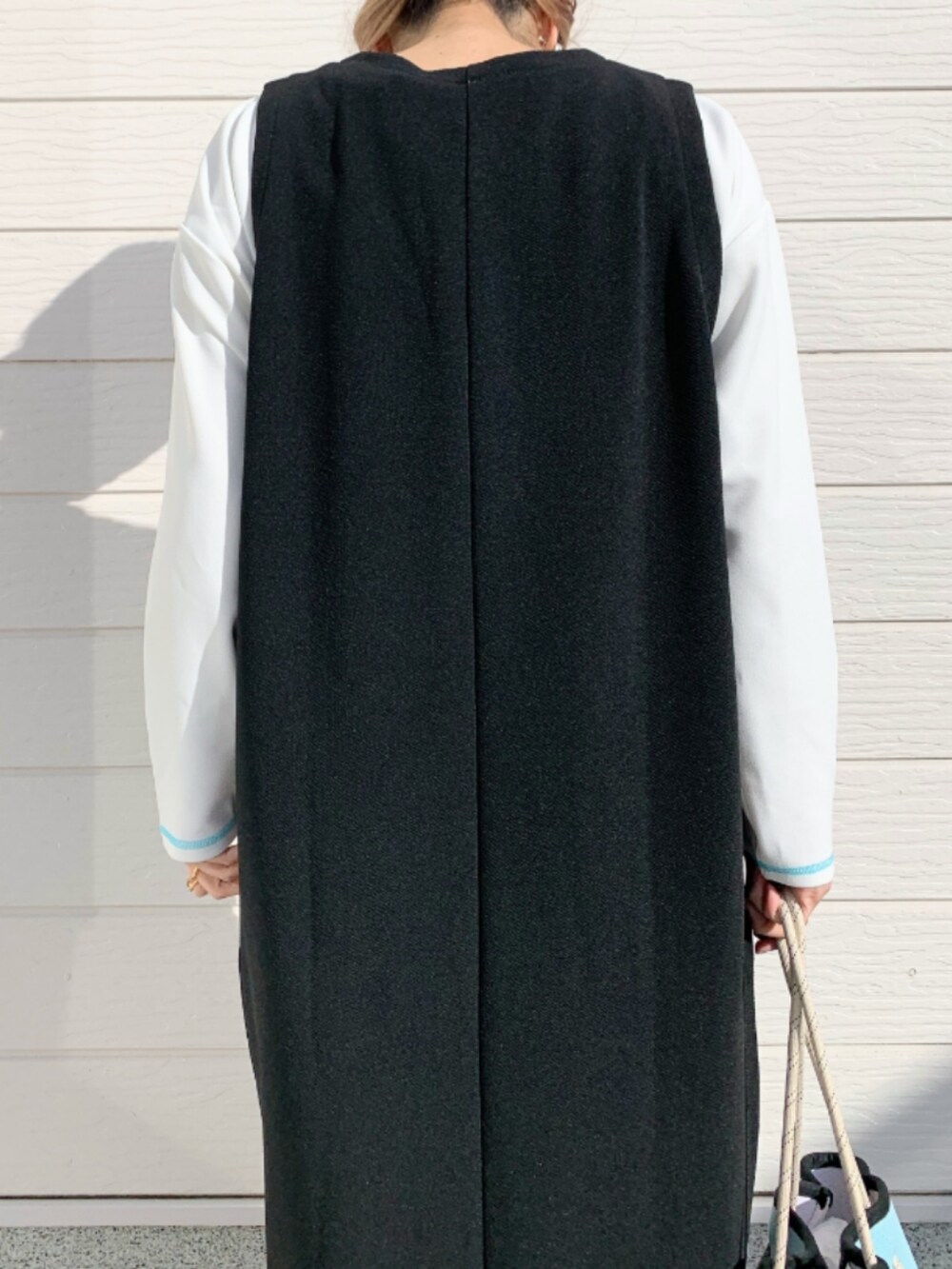 ブルー系のトートバッグ、ブラック系のワンピース、ホワイト系のTシャツ/カットソーを着用したレディースの冬コーディネートの5枚目の写真