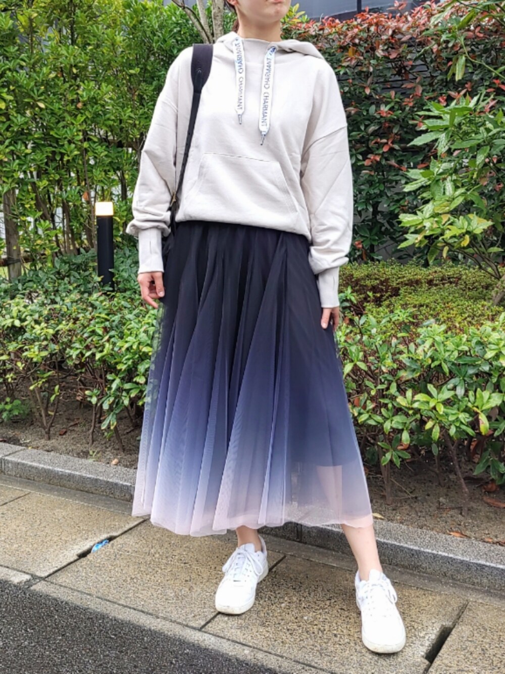 ブラック系のスカート、ベージュ系のパーカー、ホワイト系のスニーカーを着用したレディースの秋コーディネートの2枚目の写真