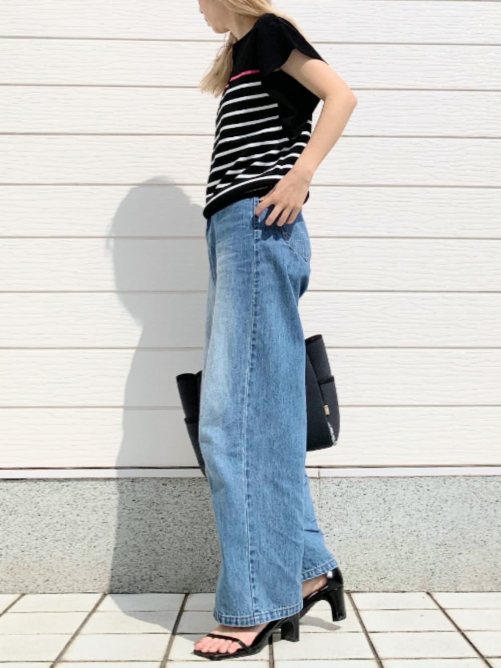 ブルー系のトートバッグ、ブルー系のデニムパンツ、ブラック系のニット/セーターを着用したレディースの春コーディネートの2枚目の写真