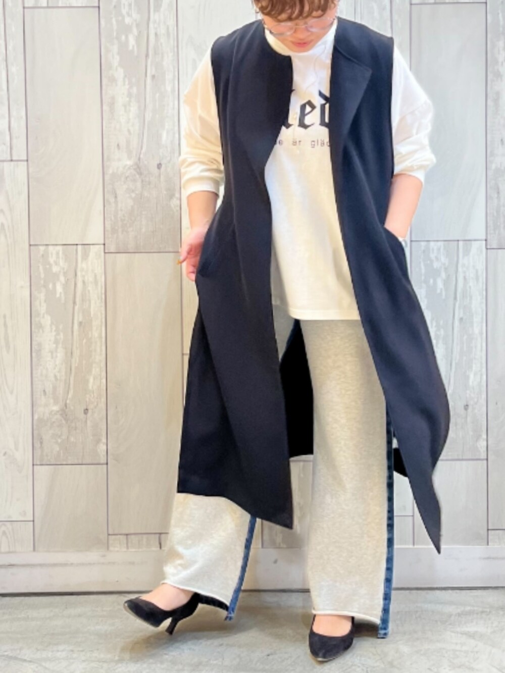 グレー系のデニムパンツ、ホワイト系のTシャツ/カットソー、ブラック系のベストを着用したレディースの春コーディネートの2枚目の写真