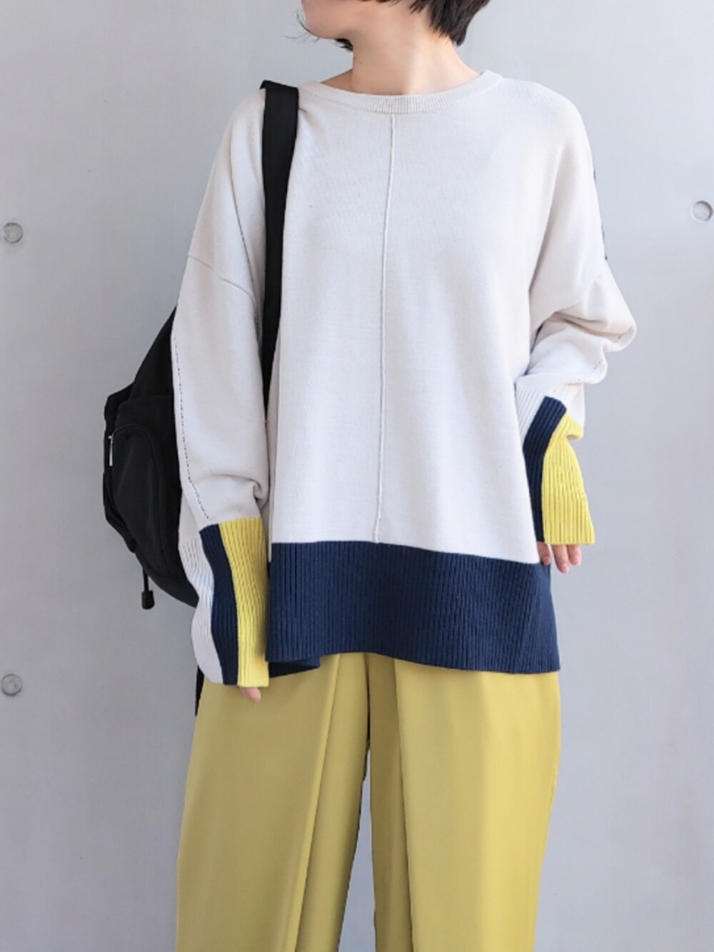 ブラック系のバックパック/リュック、グリーン系のスラックス、ベージュ系のニット/セーターを着用したレディースの冬コーディネートの3枚目の写真