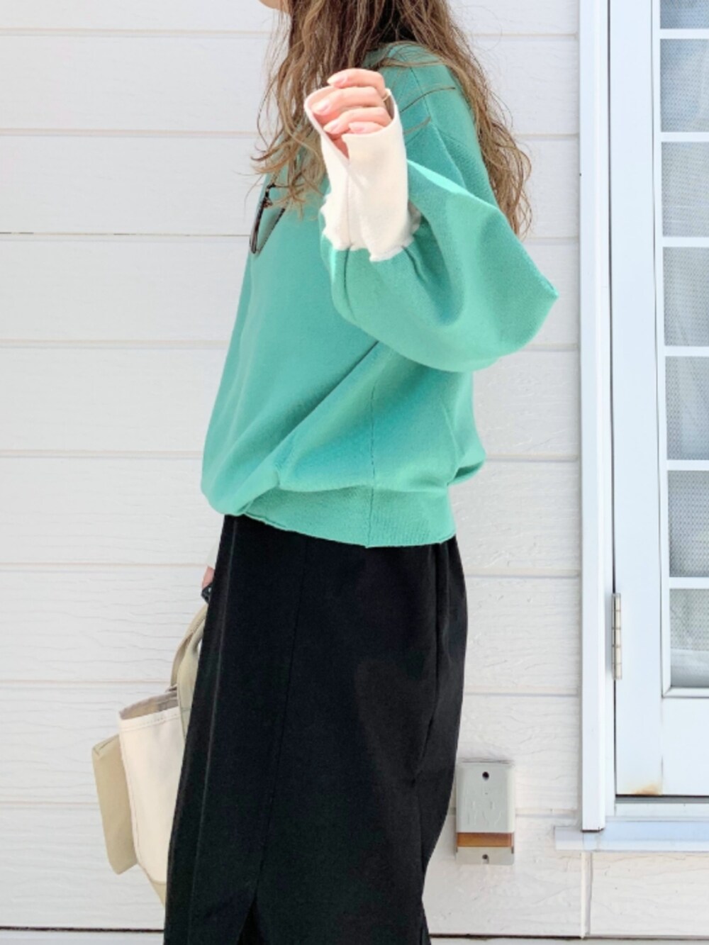 ベージュ系のトートバッグ、ブラック系のスカート、グリーン系のニット/セーターを着用したレディースの夏コーディネートの5枚目の写真