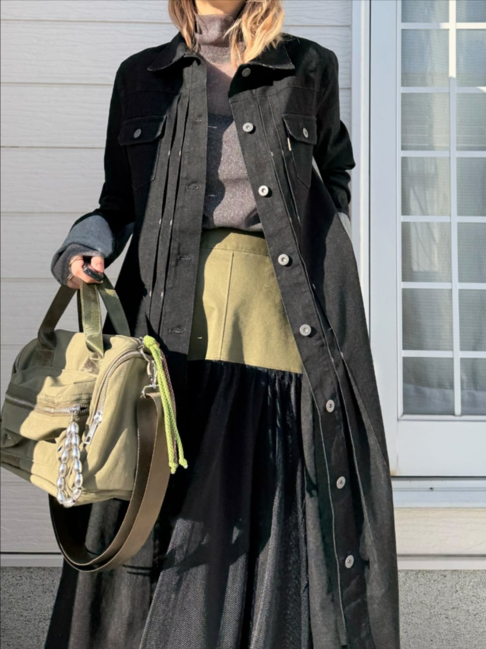 グリーン系のスカート、グリーン系のボストンバッグ、ブラック系のデニムジャケットを着用したレディースの冬コーディネートの4枚目の写真