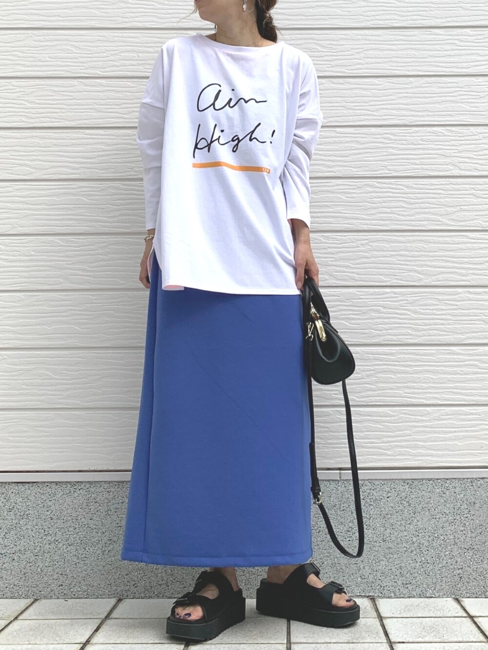 ブラック系のサンダル、ブラック系のショルダーバッグ、ブルー系のスカートを着用したレディースの春コーディネートの2枚目の写真