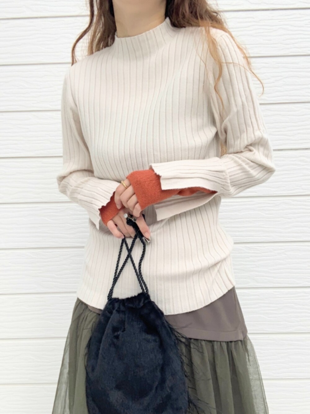 ブラウン系のブーツ、ホワイト系のニット/セーター、ブラック系のクラッチバッグを着用したレディースの秋コーディネートの4枚目の写真