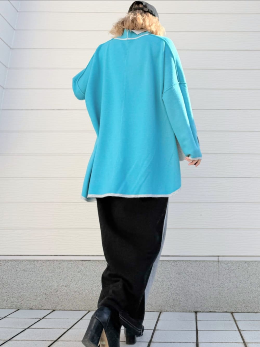 グレー系のニット/セーター、グレー系のスカート、ブラック系のキャップを着用したレディースの秋コーディネートの3枚目の写真