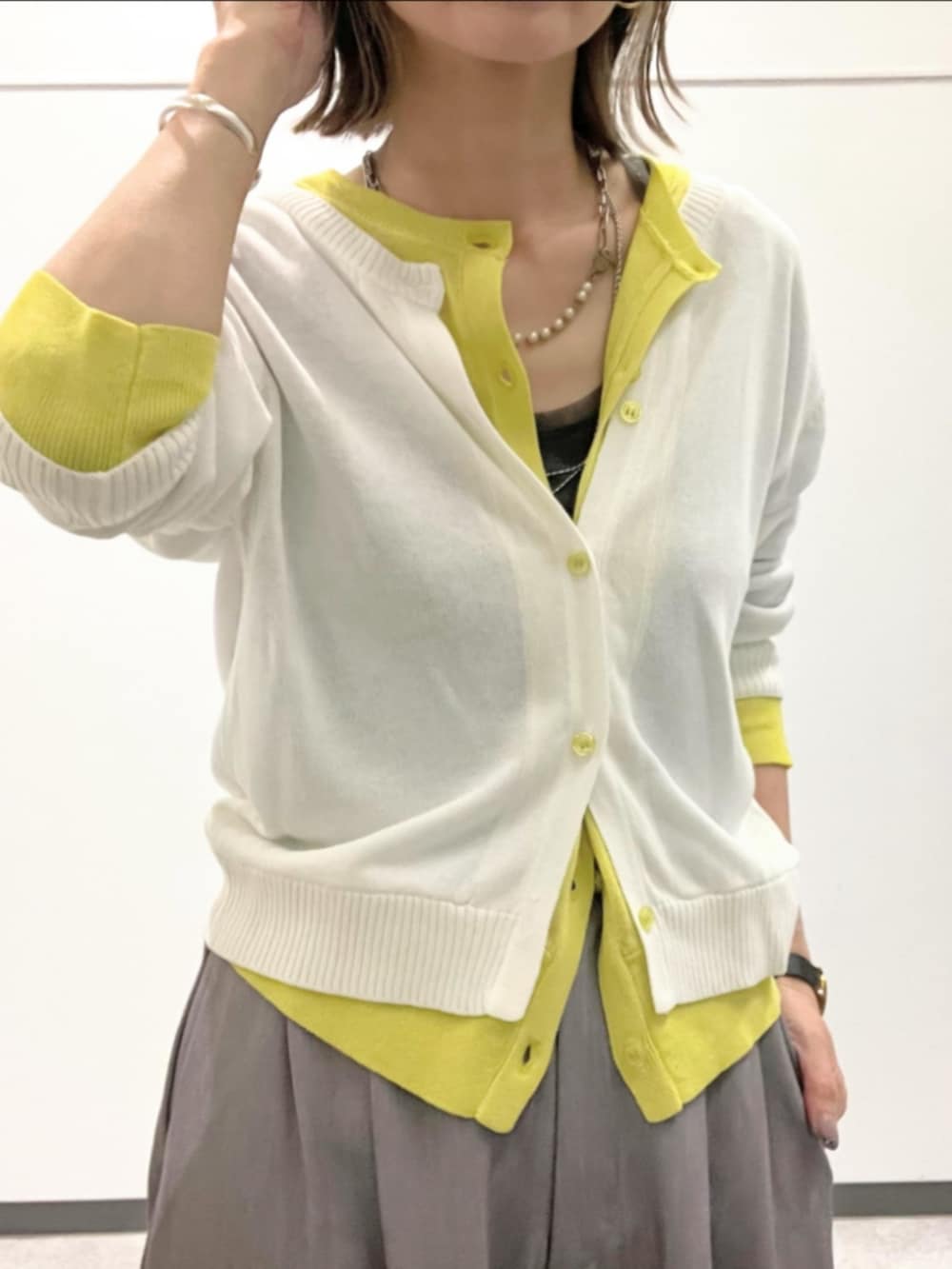 グレー系のスラックス、ホワイト系のTシャツ/カットソー、ホワイト系のカーディガン/ボレロを着用したレディースの春コーディネートの4枚目の写真