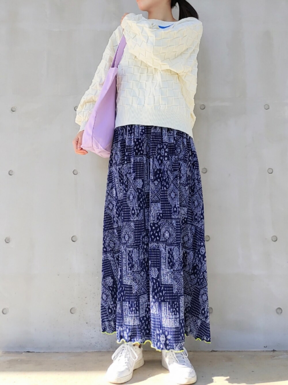 パープル系のトートバッグ、ホワイト系のニット/セーター、ホワイト系のスニーカーを着用したレディースの冬コーディネートの2枚目の写真