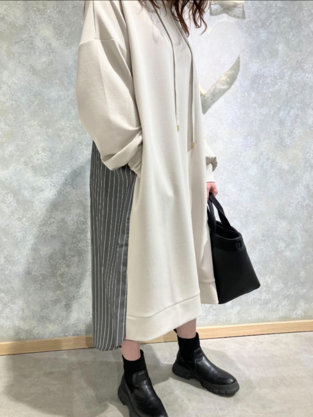 ブラック系のトートバッグ、ホワイト系のワンピースを着用したレディースの冬コーディネートの3枚目の写真