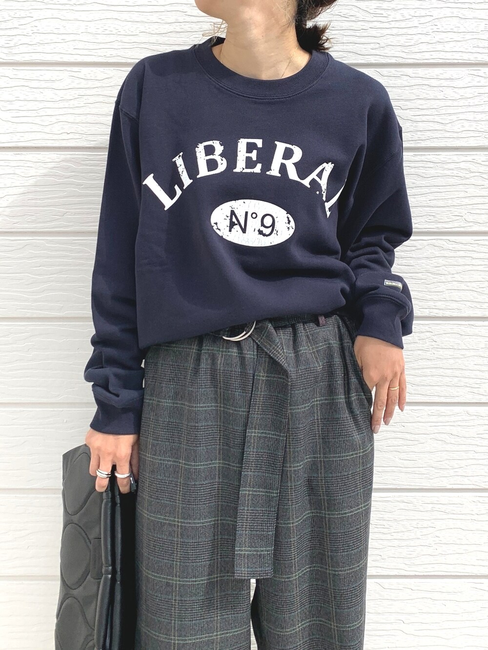 ブラック系のクラッチバッグ、シルバー系のスニーカー、ブルー系のスウェットを着用したレディースの秋コーディネートの4枚目の写真