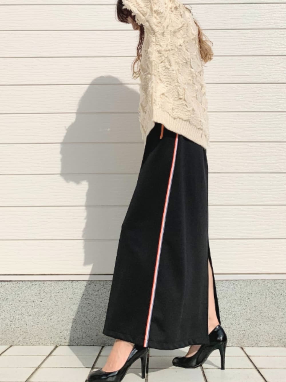 ブラック系のスカート、ホワイト系のニット/セーターを着用したレディースの秋コーディネートの2枚目の写真