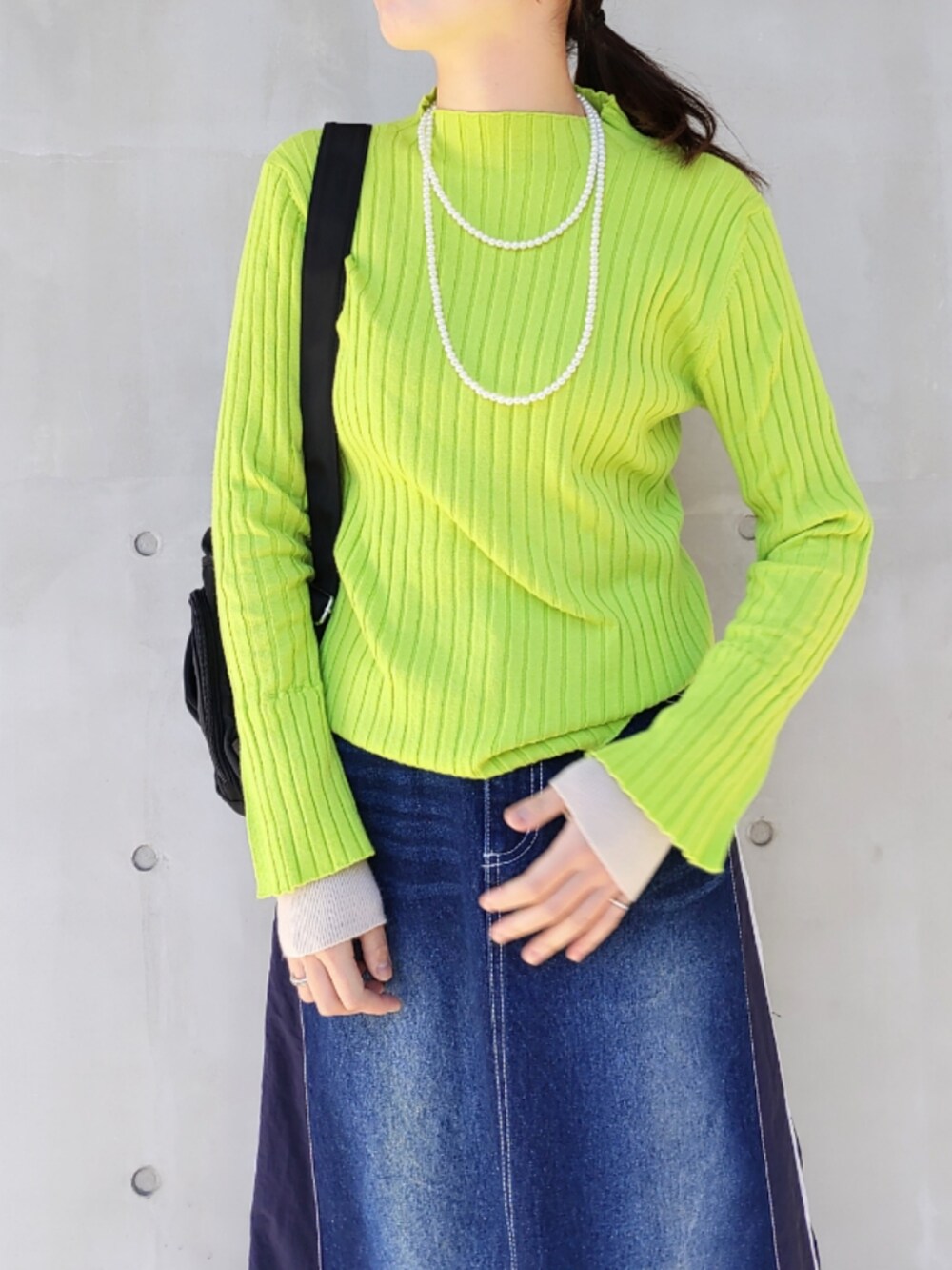 ブルー系のデニムスカート、グリーン系のニット/セーター、ブラック系のバックパック/リュックを着用したレディースの冬コーディネートの5枚目の写真