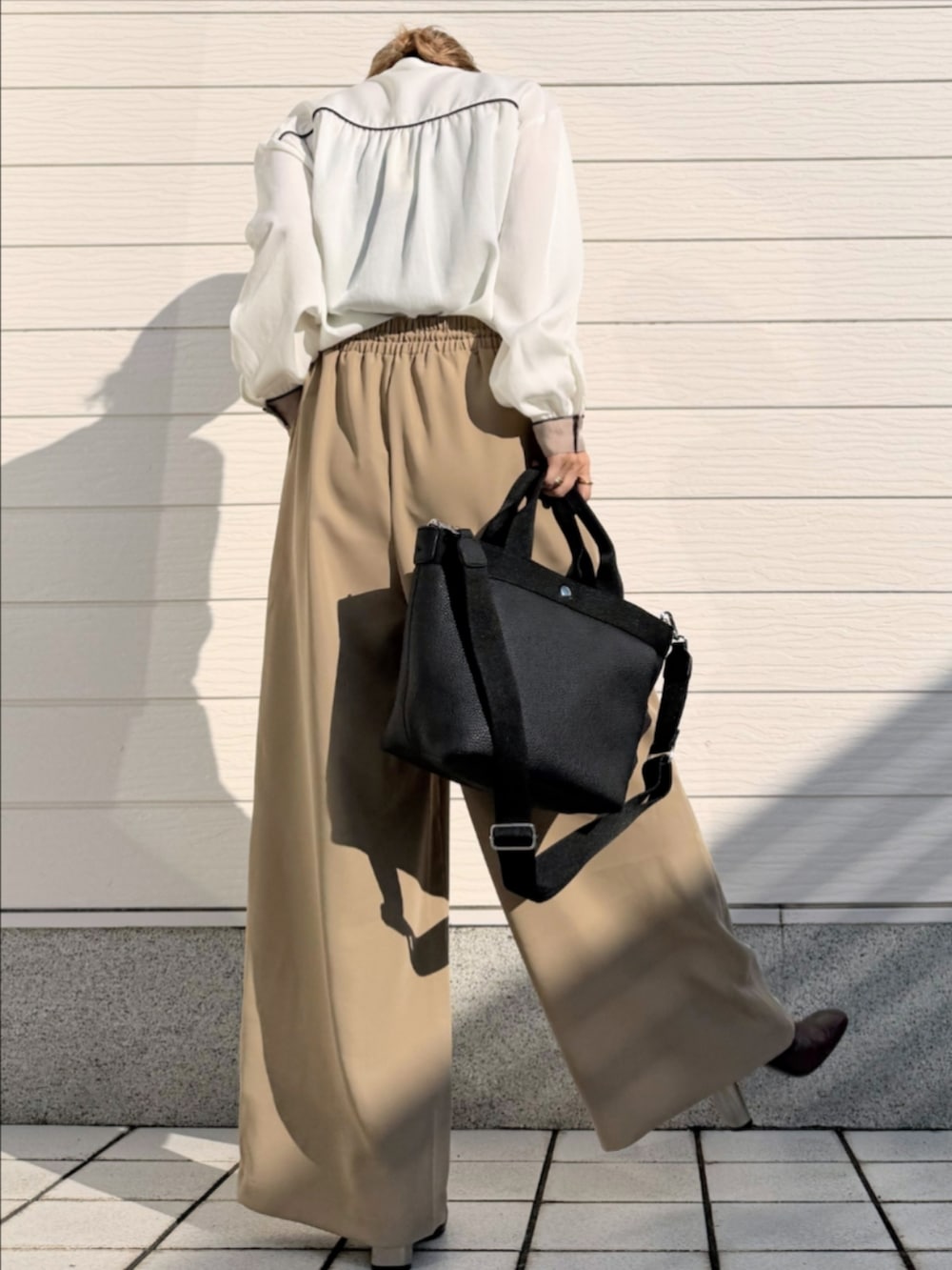ブラック系のトートバッグ、ベージュ系のその他パンツ、ホワイト系のシャツ/ブラウスを着用したレディースの冬コーディネートの3枚目の写真