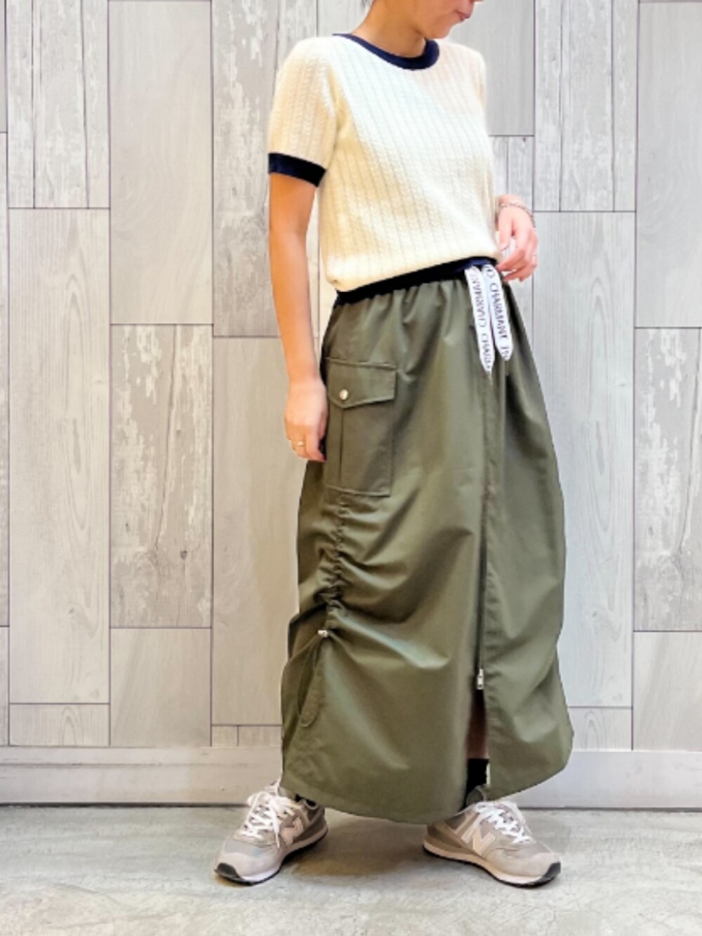 グリーン系のスカート、ホワイト系のニット/セーターを着用したレディースの夏コーディネートの2枚目の写真