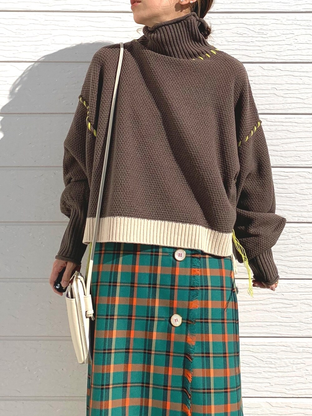 ブラウン系のニット/セーター、グリーン系のスカート、ブラウン系のブーツを着用したレディースの秋コーディネートの4枚目の写真