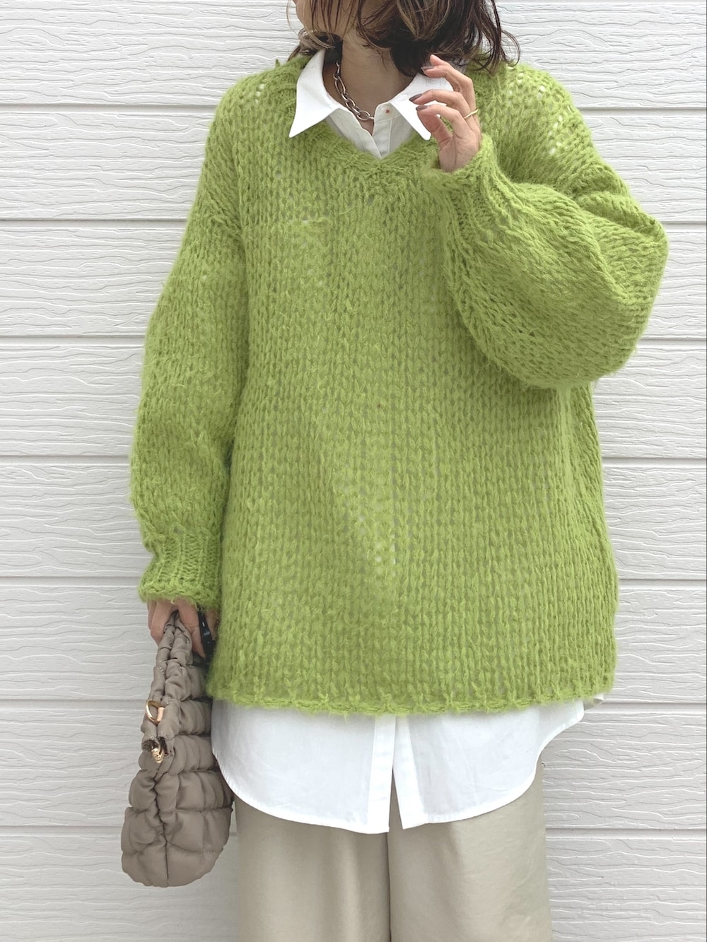 グリーン系のニット/セーター、ホワイト系のシャツ/ブラウス、ベージュ系のショルダーバッグを着用したレディースの冬コーディネートの4枚目の写真