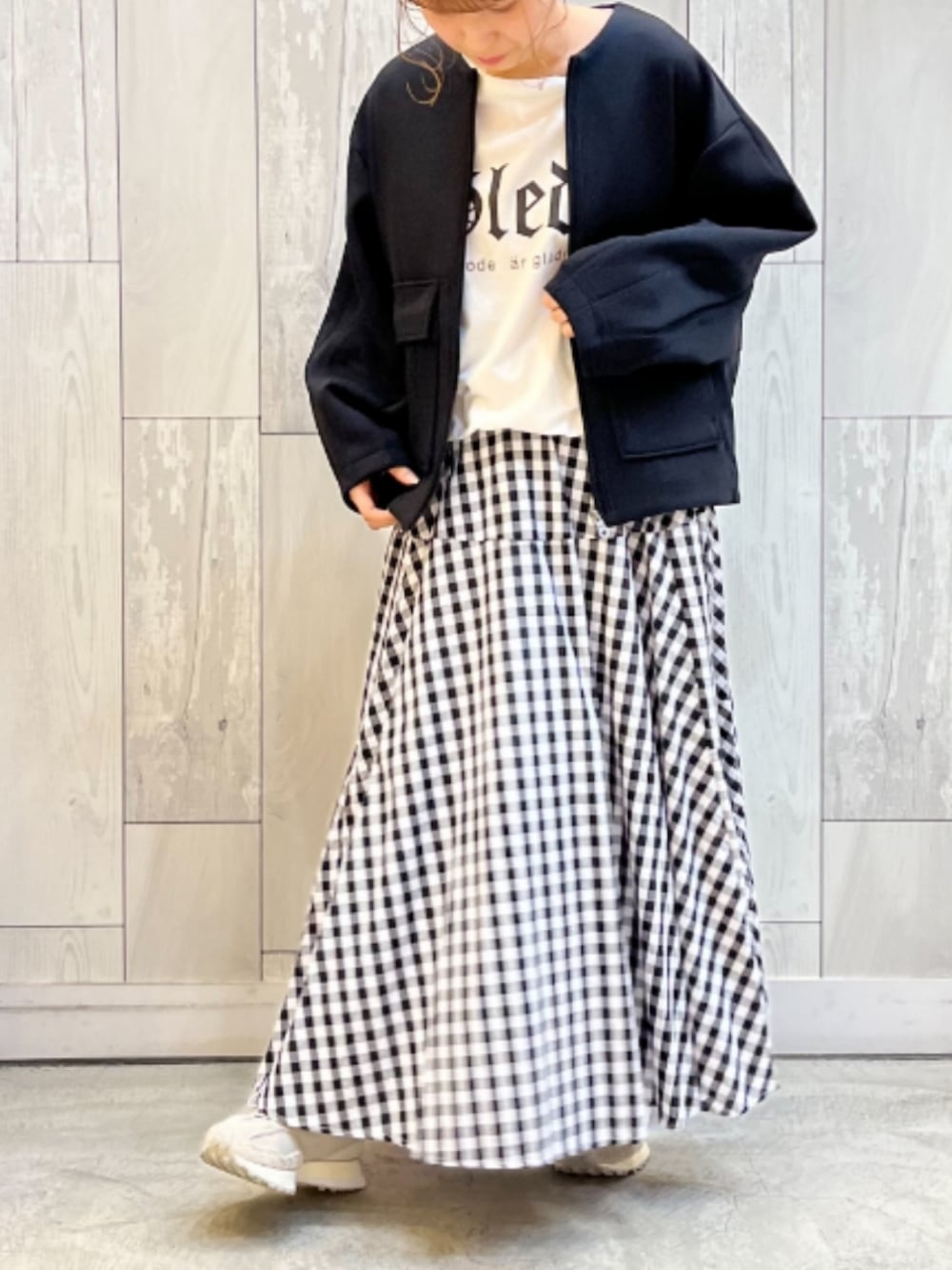 ブラック系のノーカラージャケット、ホワイト系のTシャツ/カットソー、ブラック系のスカートを着用したレディースの春コーディネートの2枚目の写真