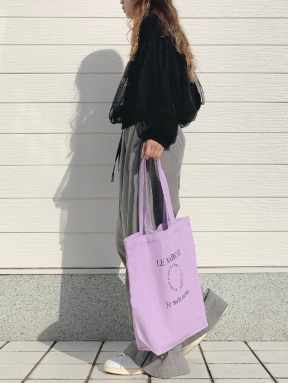 パープル系のトートバッグ、ホワイト系のスニーカー、グレー系のその他パンツを着用したレディースの秋コーディネートの2枚目の写真