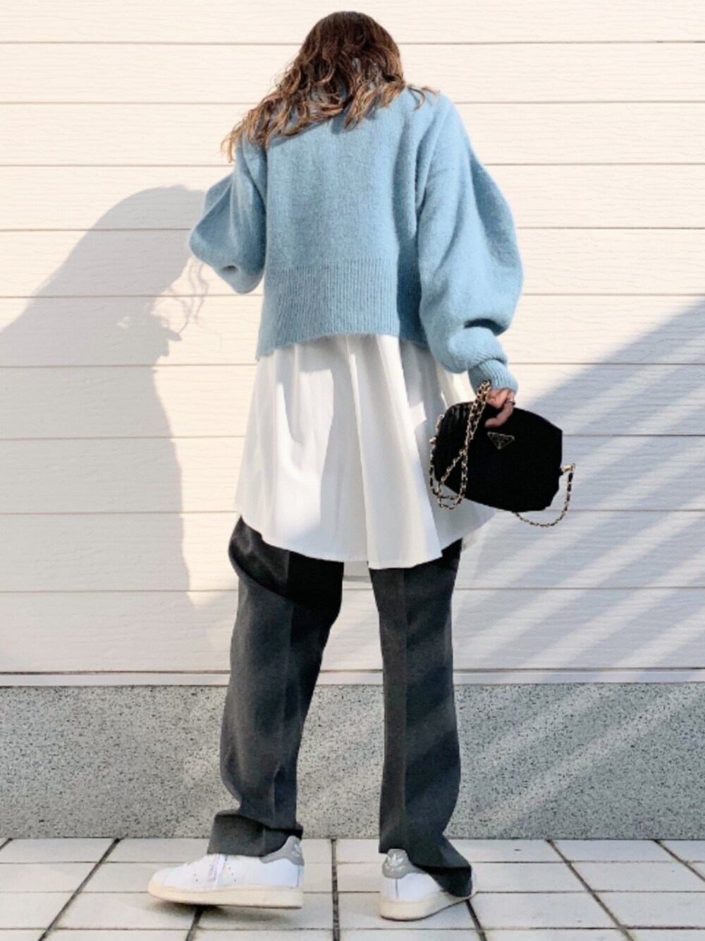 グレー系のその他パンツ、ホワイト系のスニーカー、ブルー系のニット/セーターを着用したレディースの冬コーディネートの2枚目の写真