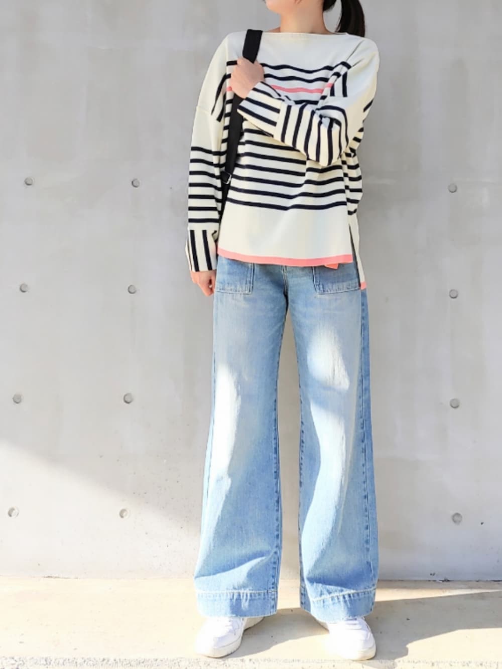 ブルー系のデニムパンツ、ホワイト系のスニーカー、ブラック系のバックパック/リュックを着用したレディースの冬コーディネートの2枚目の写真