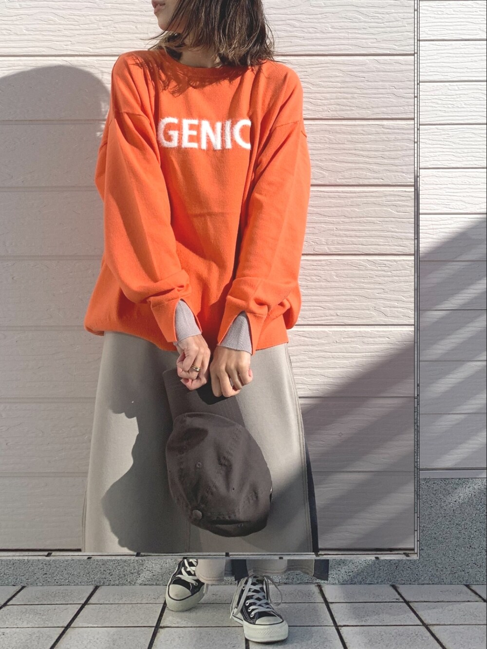 ベージュ系のスカート、オレンジ系のニット/セーター、ブラック系のスニーカーを着用したレディースの冬コーディネートの4枚目の写真