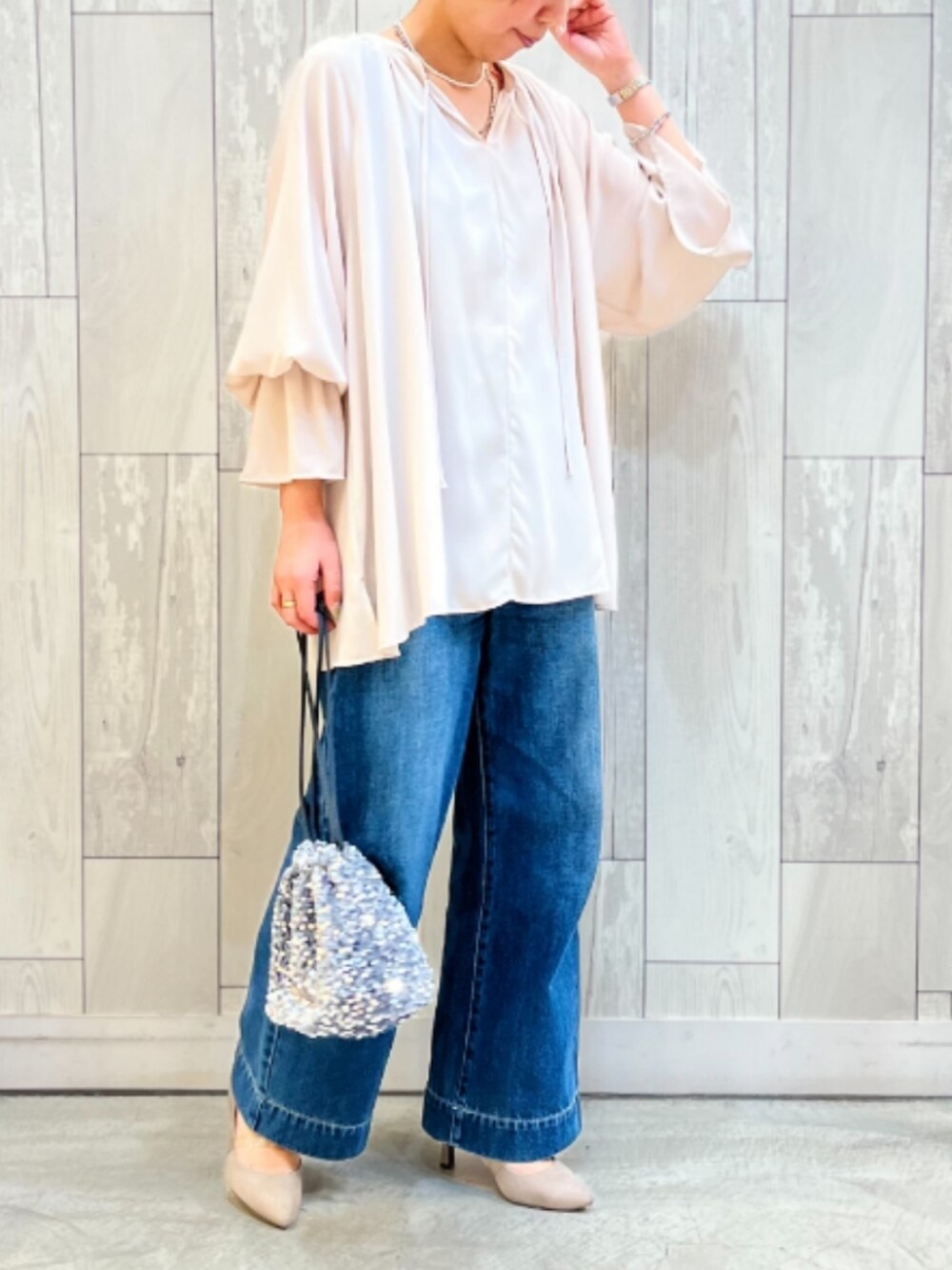 ブルー系のデニムパンツ、ベージュ系のシャツ/ブラウス、シルバー系のハンドバッグを着用したレディースの冬コーディネートの2枚目の写真