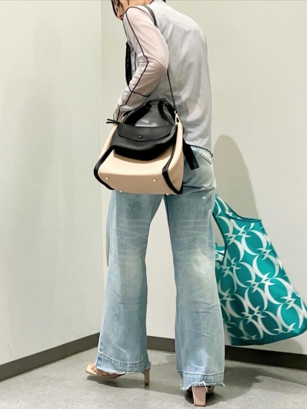 ベージュ系のハンドバッグ、グレー系のTシャツ/カットソー、ブルー系のデニムパンツを着用したレディースの秋コーディネートの2枚目の写真