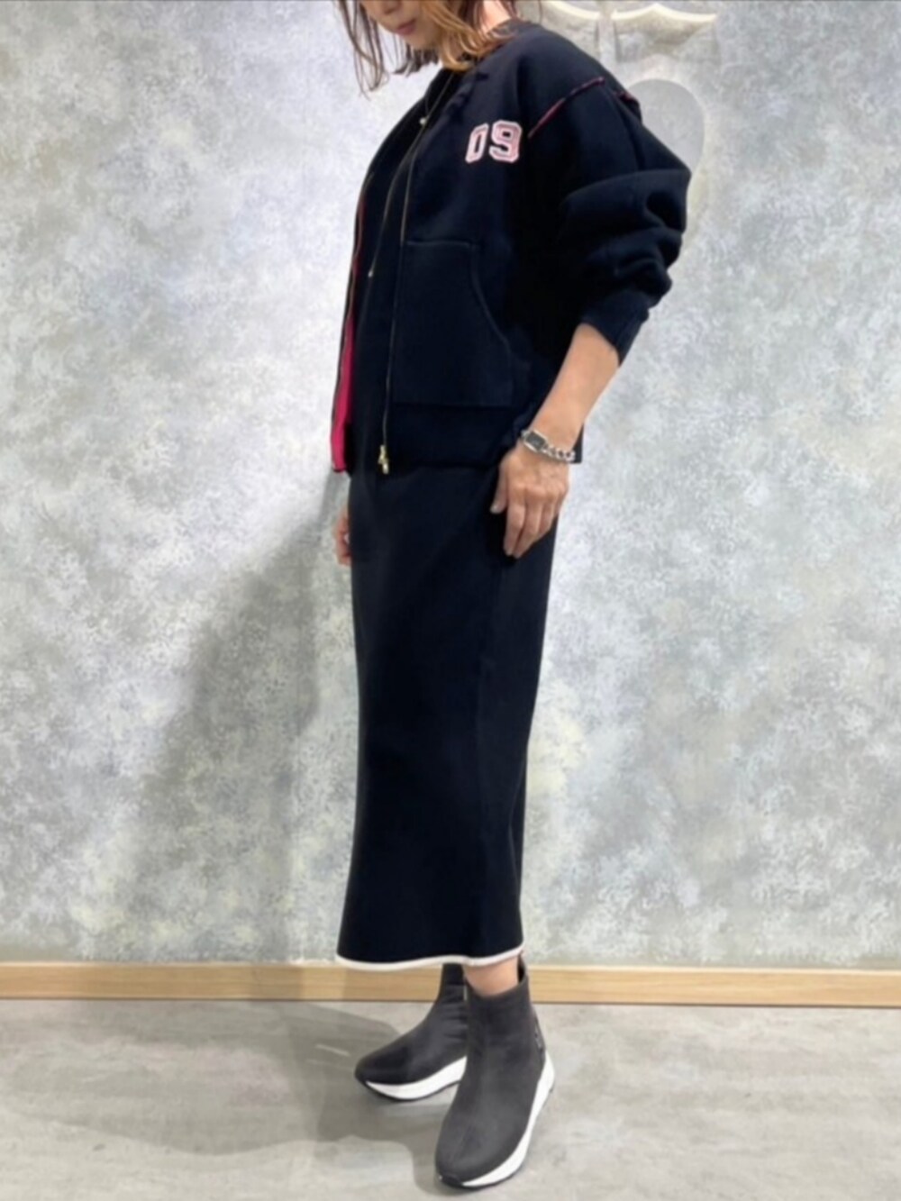 グレー系のブーツ、ブラック系のブルゾン、ブラック系のワンピースを着用したレディースの秋コーディネートの2枚目の写真