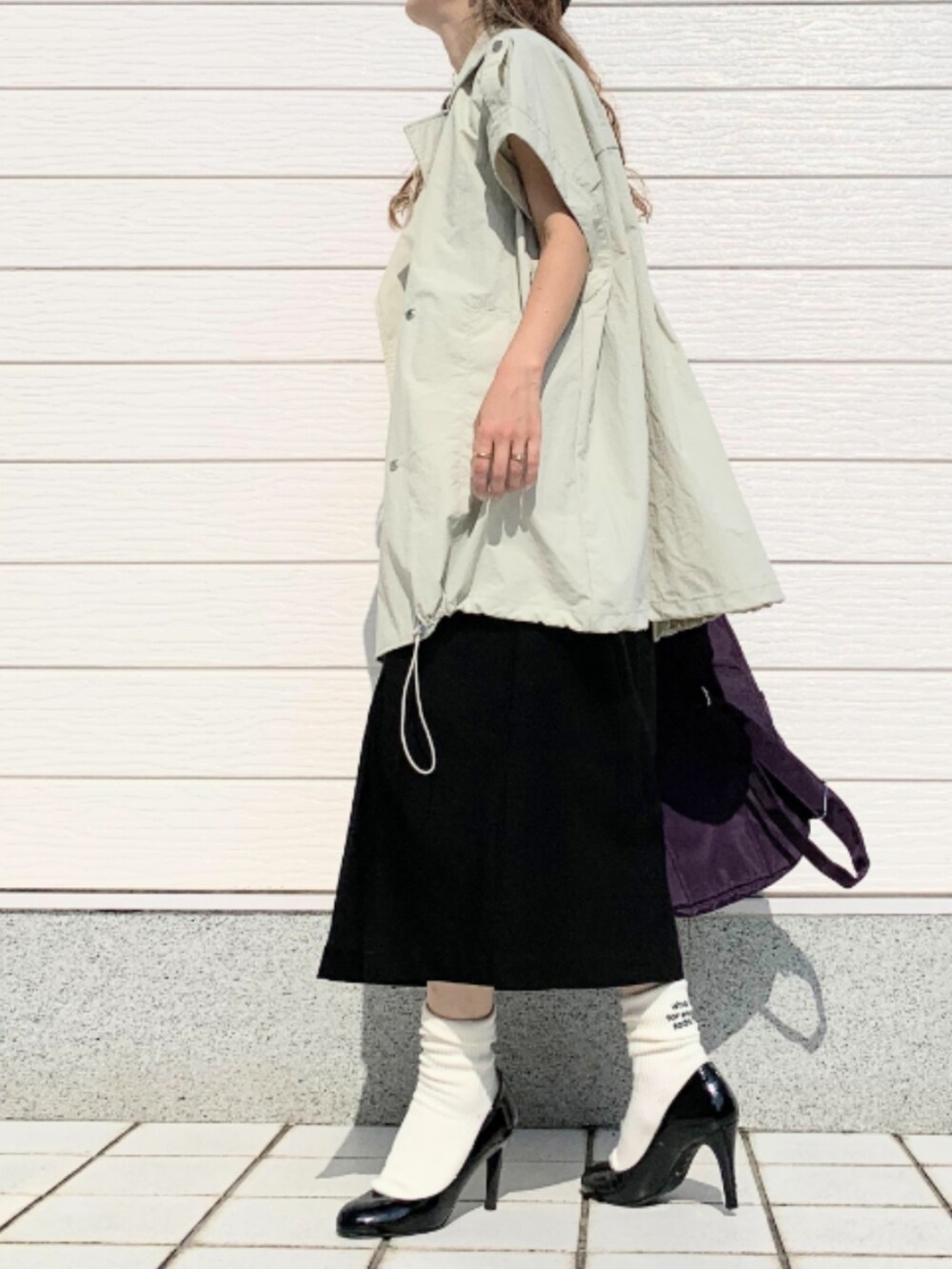 グレー系のTシャツ/カットソー、ブラック系のスカート、パープル系のバックパック/リュックを着用したレディースの夏コーディネートの2枚目の写真