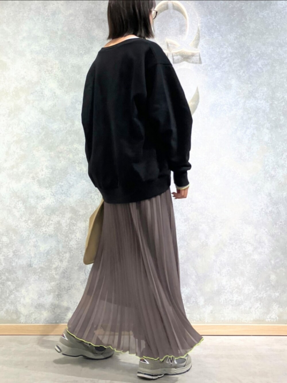 グリーン系のスカート、ベージュ系のトートバッグ、ブラック系のスウェットを着用したレディースの秋コーディネートの2枚目の写真