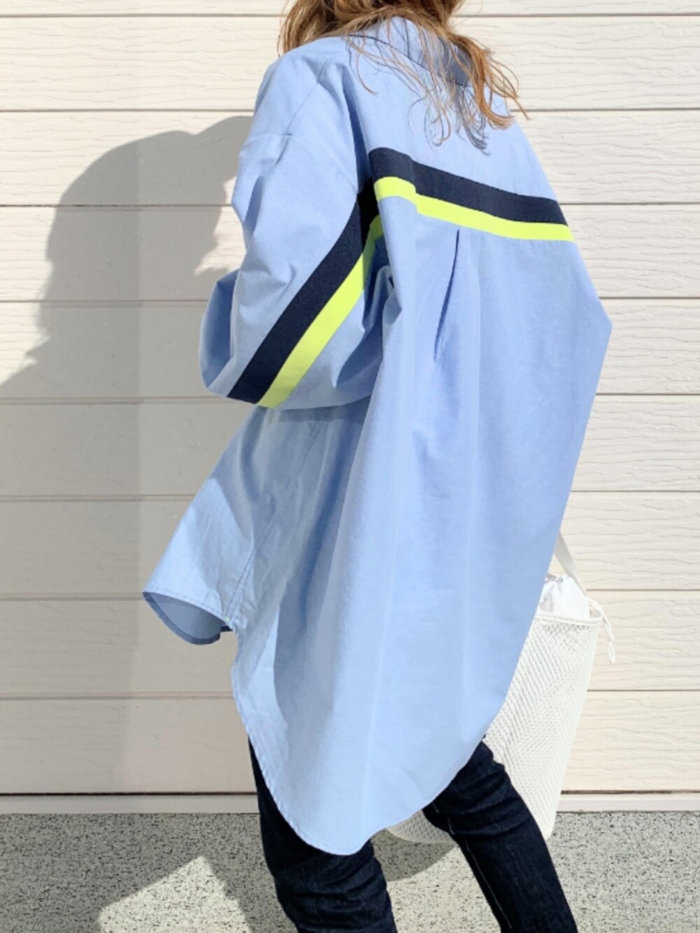 ブルー系のデニムパンツ、シルバー系のスニーカー、ホワイト系のショルダーバッグを着用したレディースの冬コーディネートの5枚目の写真