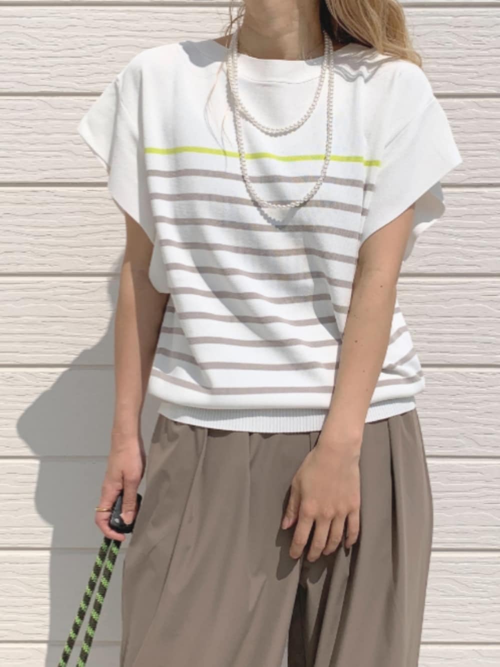 グレー系のその他パンツ、グレー系のトートバッグ、ホワイト系のニット/セーターを着用したレディースの春コーディネートの3枚目の写真