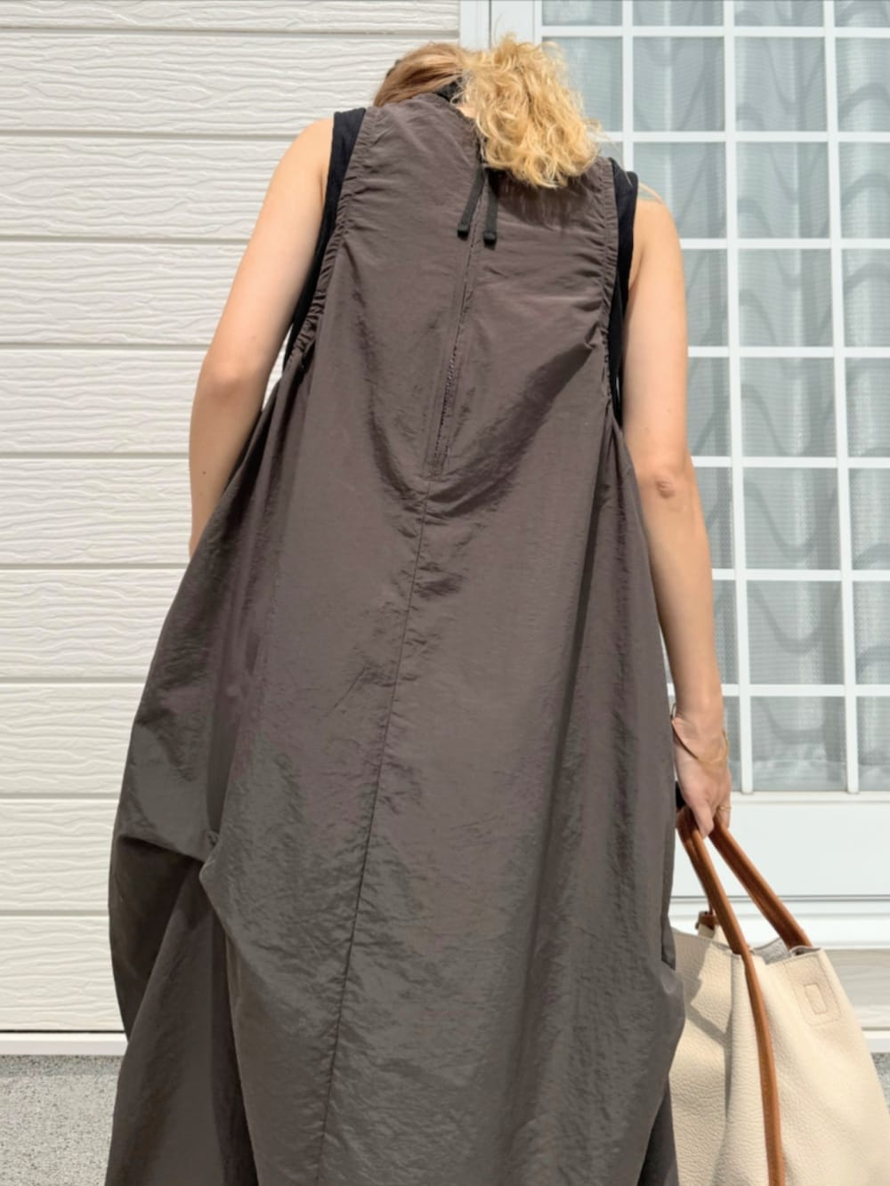 ブラック系のサンダル、ホワイト系のハンドバッグ、グレー系のワンピースを着用したレディースの夏コーディネートの5枚目の写真