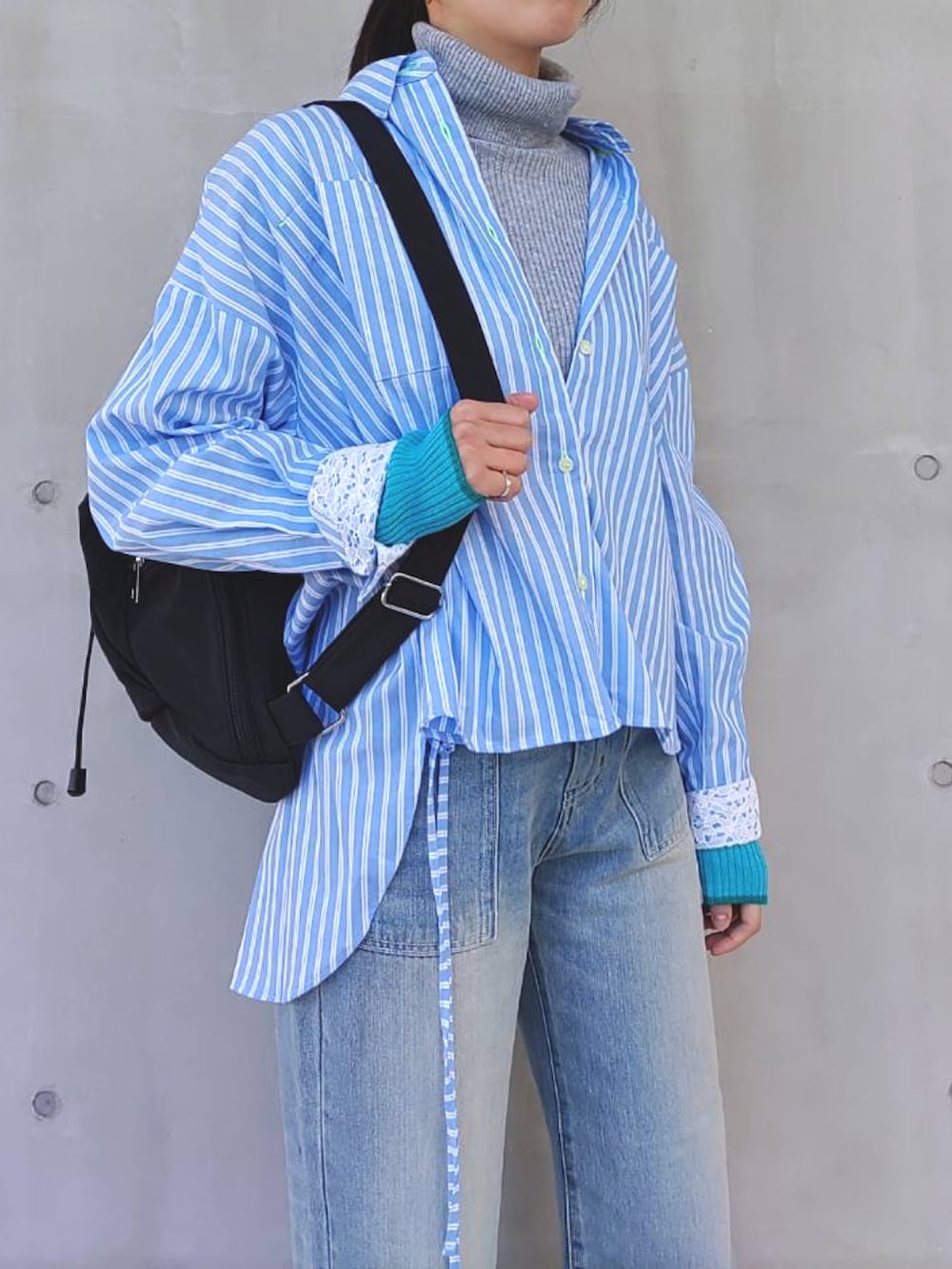 ブルー系のシャツ/ブラウス、グレー系のニット/セーター、ブラック系のバックパック/リュックを着用したレディースの冬コーディネートの2枚目の写真