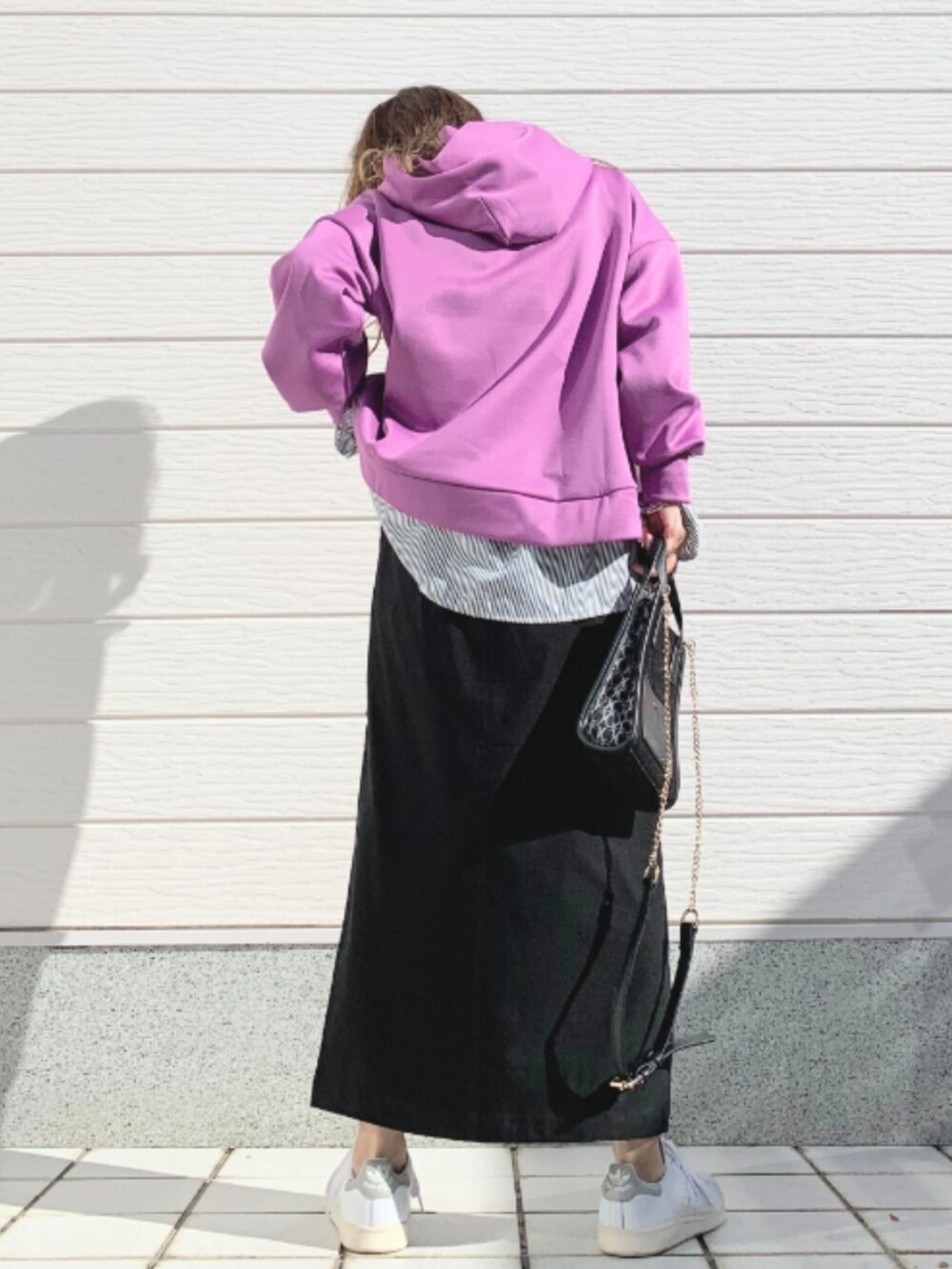 ブラック系のショルダーバッグ、ホワイト系のスニーカー、ブラック系のスカートを着用したレディースの秋コーディネートの3枚目の写真