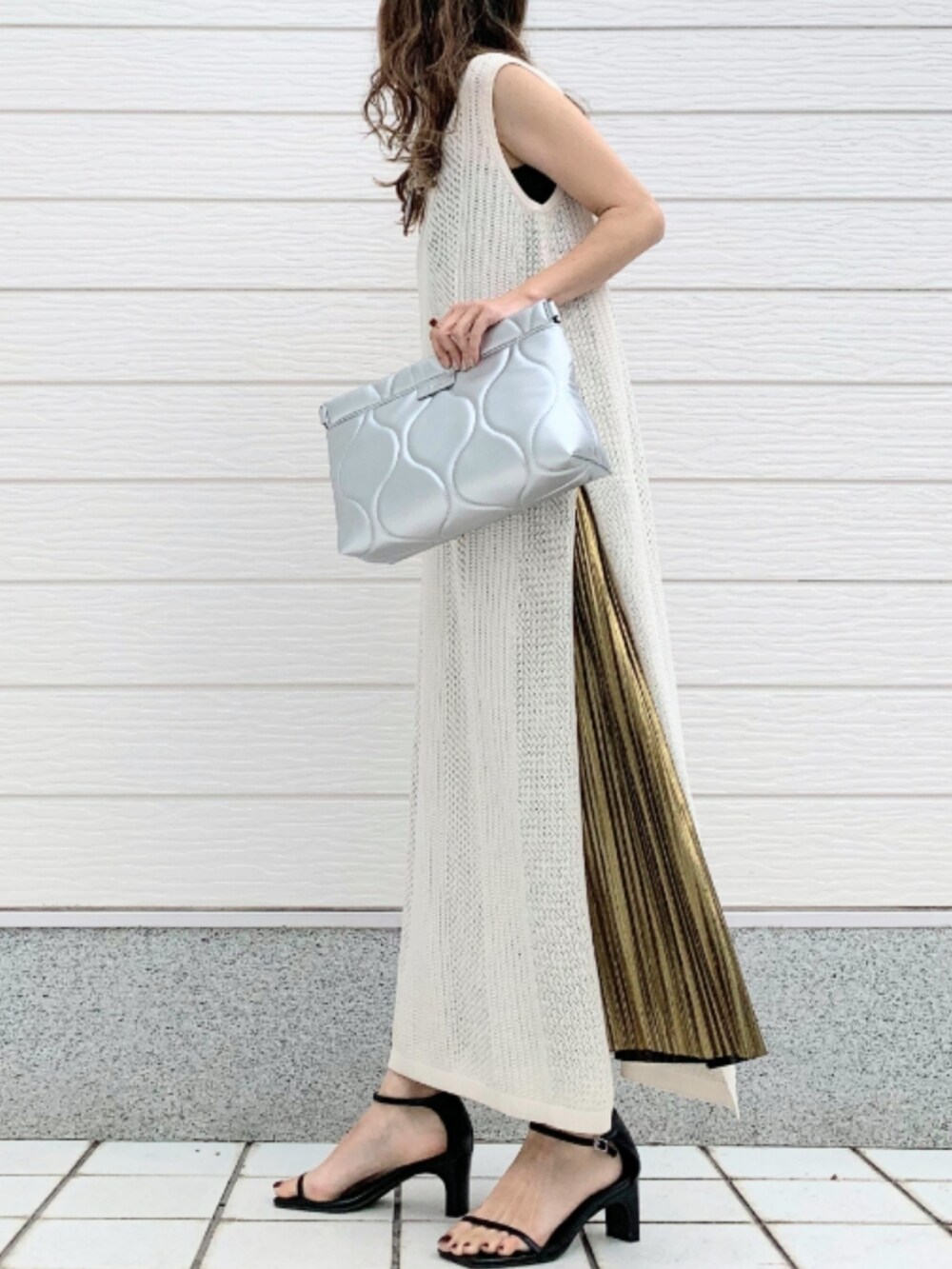 シルバー系のクラッチバッグ、ゴールド系のスカート、ホワイト系のワンピースを着用したレディースの春コーディネートの3枚目の写真