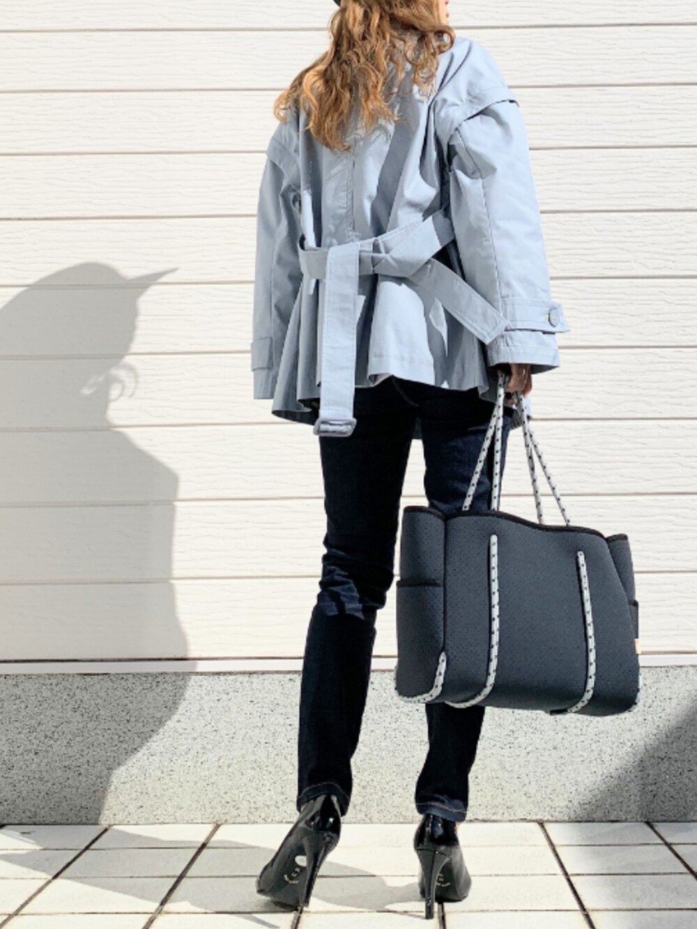 ブルー系のデニムパンツ、ブルー系のトートバッグ、ホワイト系のスウェットを着用したレディースの冬コーディネートの2枚目の写真