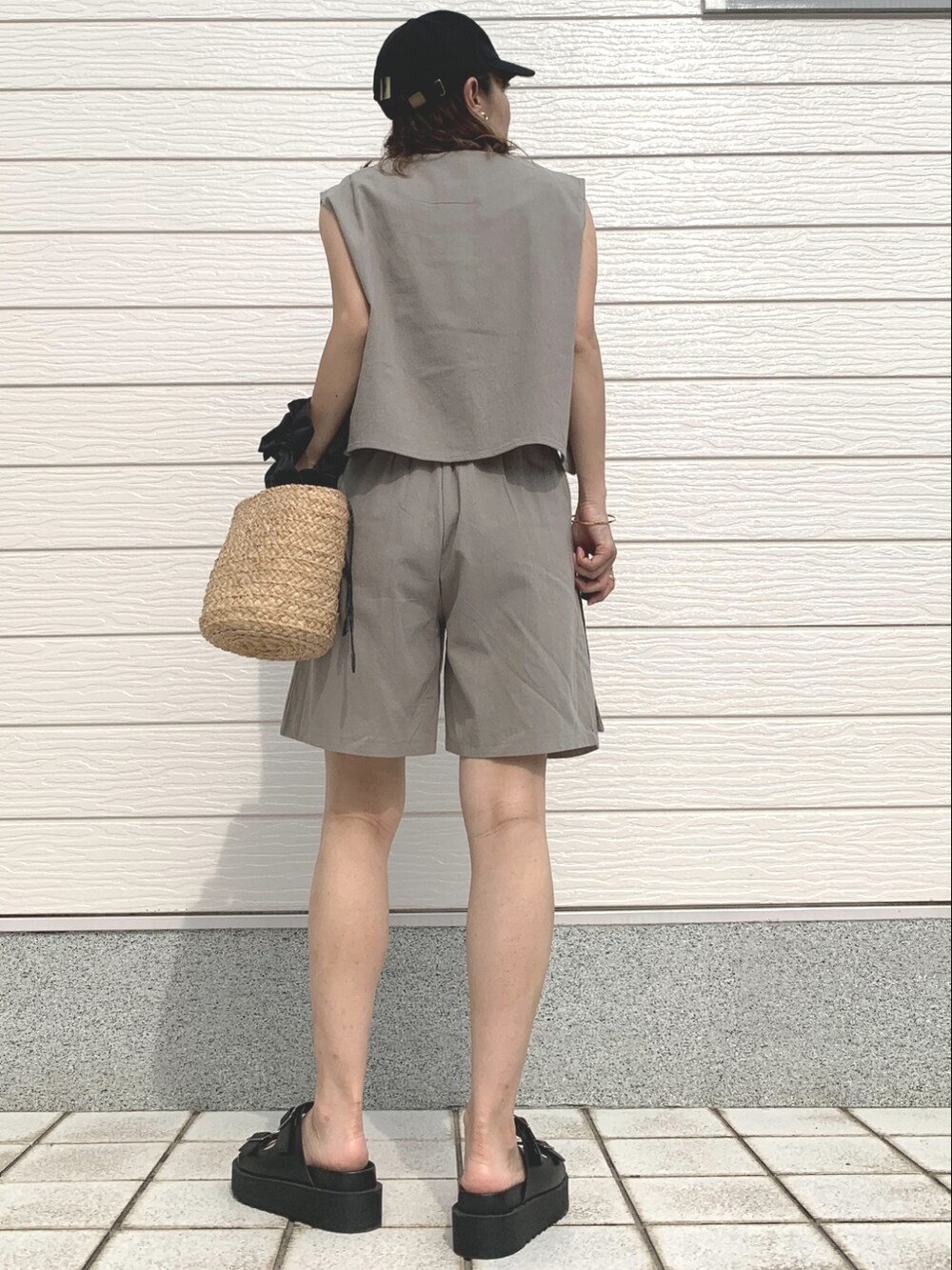 ブラック系のかごバッグ、ブラック系のサンダル、グリーン系のセットアップを着用したレディースの春コーディネートの3枚目の写真