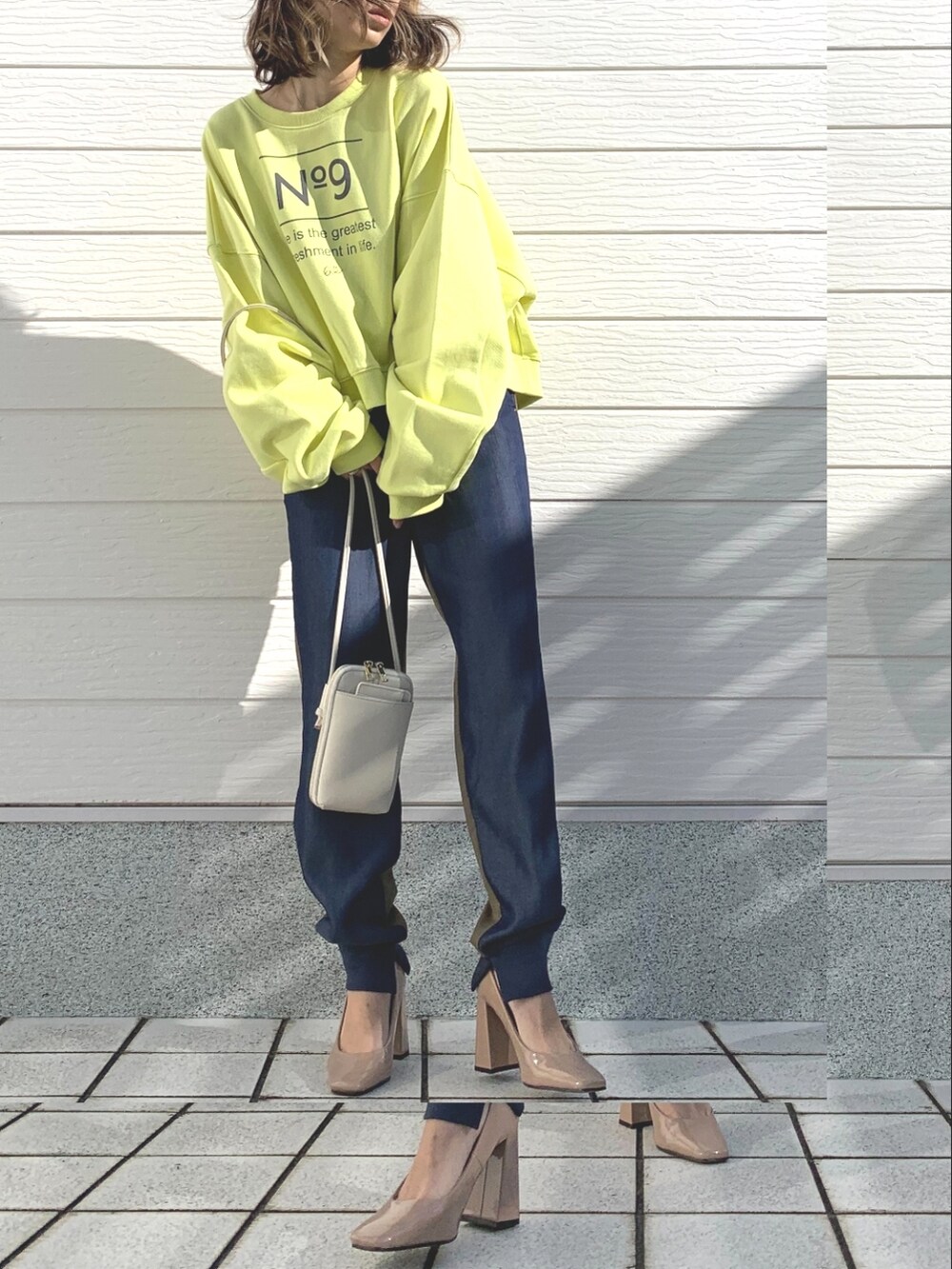 グリーン系のデニムパンツ、ホワイト系のショルダーバッグ、イエロー系のスウェットを着用したレディースの冬コーディネートの2枚目の写真