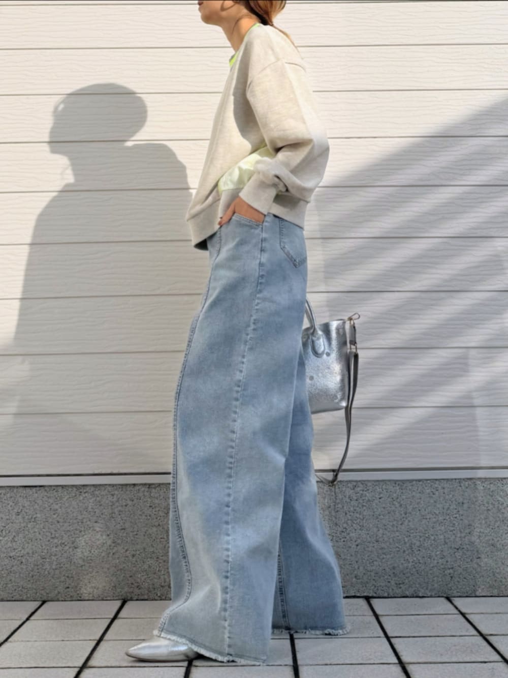 ブルー系のデニムパンツ、シルバー系のトートバッグ、グレー系のカーディガン/ボレロを着用したレディースの冬コーディネートの2枚目の写真