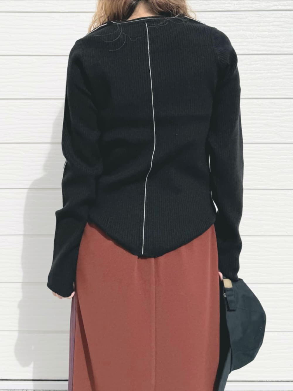 ブラック系のスニーカー、ブラック系のニット/セーター、ブラウン系のスカートを着用したレディースの秋コーディネートの5枚目の写真