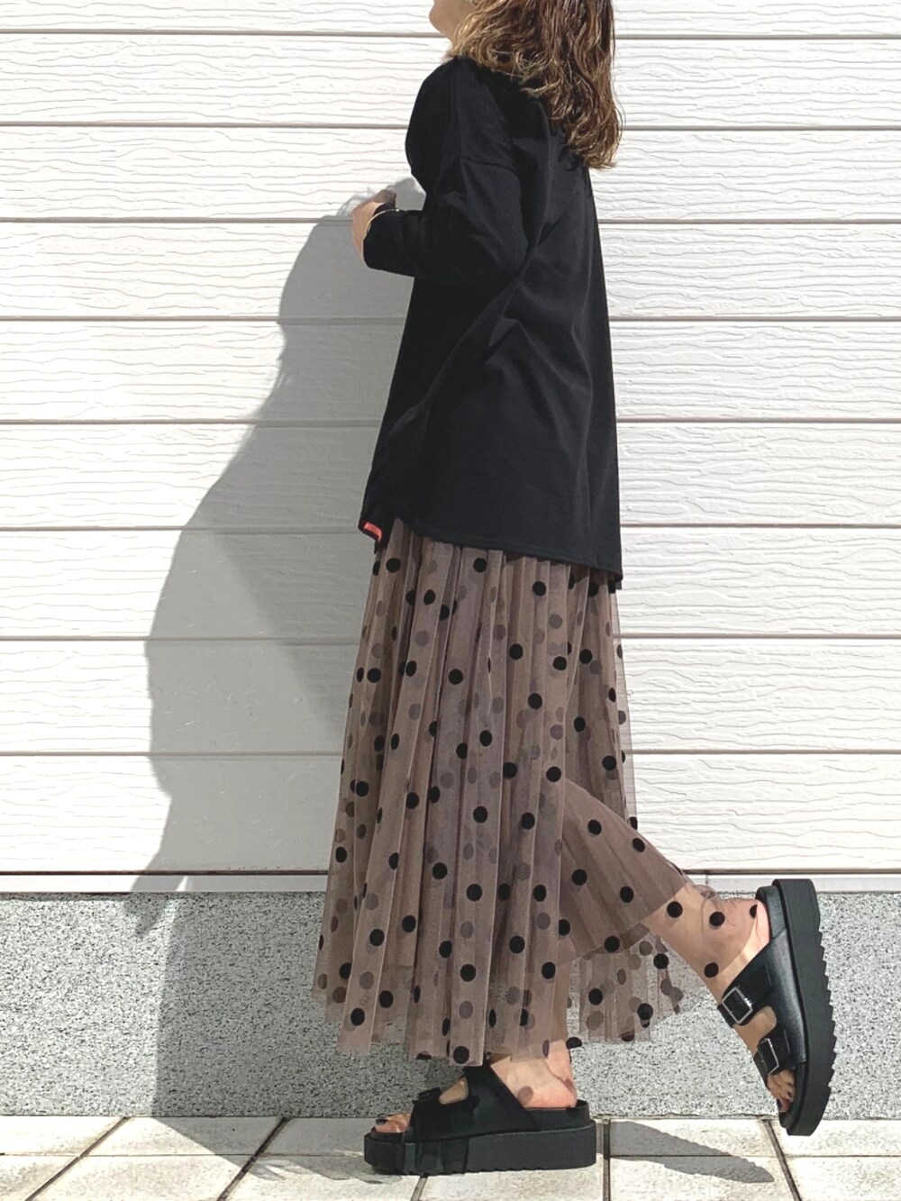 ブラック系のTシャツ/カットソー、ブラウン系のスカート、ブラック系のサンダルを着用したレディースの春コーディネートの2枚目の写真