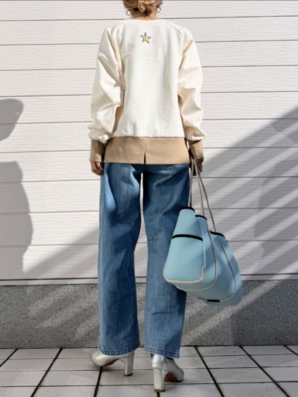 ブルー系のトートバッグ、ブルー系のデニムパンツ、ベージュ系のスウェットを着用したレディースの冬コーディネートの2枚目の写真