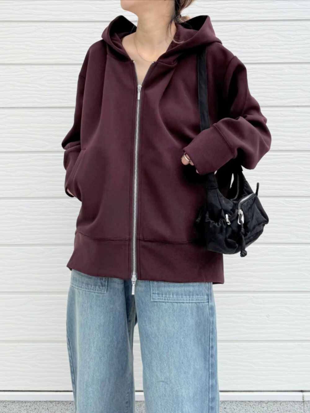 ブルー系のデニムパンツ、ブラウン系のブーツ、ブラック系のショルダーバッグを着用したレディースの秋コーディネートの4枚目の写真