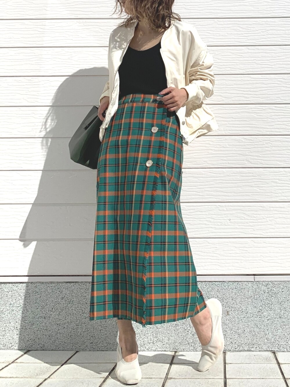 グリーン系のハンドバッグ、グリーン系のスカート、ベージュ系のブルゾンを着用したレディースの春コーディネートの2枚目の写真