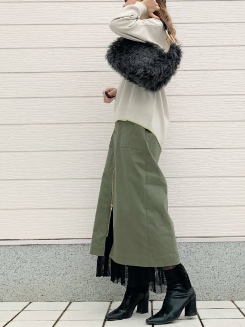 グリーン系のスカート、グレー系のハンドバッグ、グレー系のニット/セーターを着用したレディースの秋コーディネートの2枚目の写真