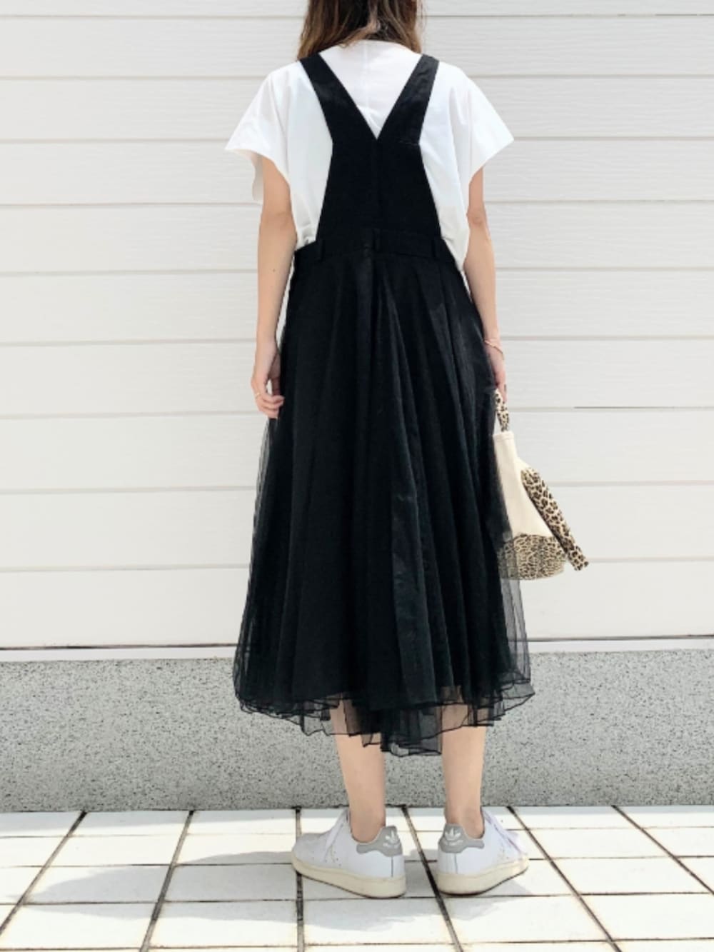 ホワイト系のスニーカー、ブラック系のジャンパースカート、ホワイト系のTシャツ/カットソーを着用したレディースの夏コーディネートの3枚目の写真