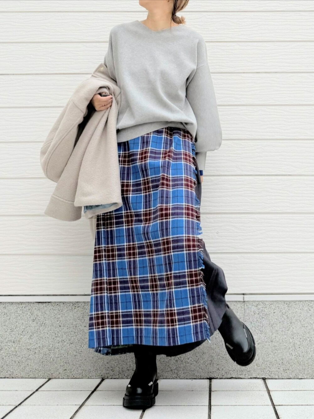 ブルー系のスカート、ブラック系のブーツ、ベージュ系のその他アウターを着用したレディースの秋コーディネートの2枚目の写真